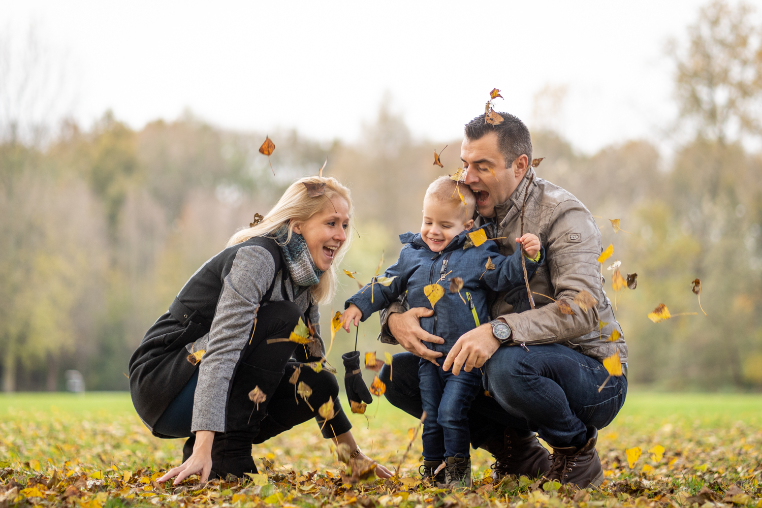 Gezin speelt met herfstbladeren in het park