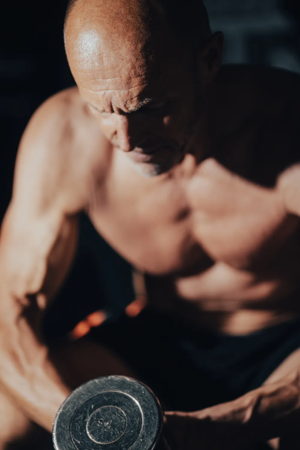 Close-up van een man met dumbbell in dramatisch licht