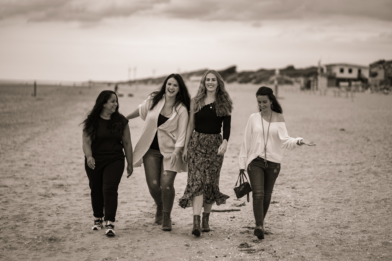 Vier vriendinnen wandelen samen over het strand, sepia