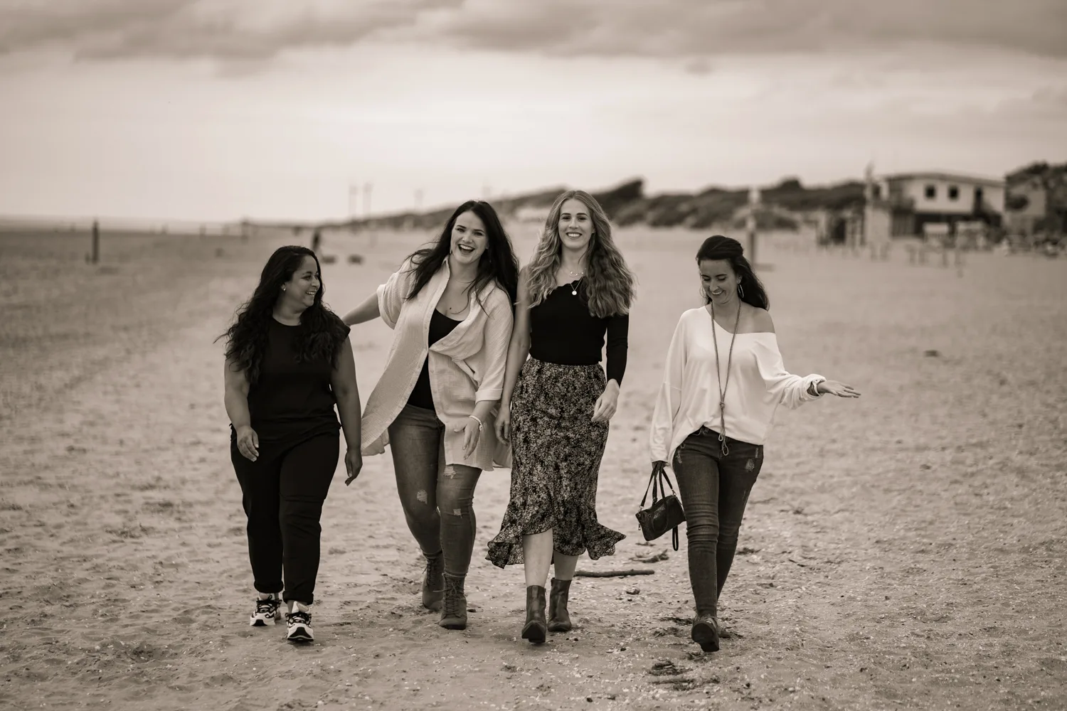 Vier vriendinnen wandelen samen over het strand, sepia